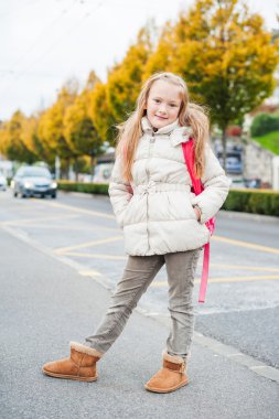 Sıcak Beyaz önlük giyen sevimli küçük kız ile sırt çantası okula gitmek için hazır