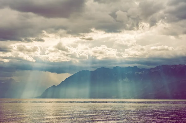 Schöne Sonnenstrahlen, die durch schwere Wolken auf die Berge und den See fallen. Farbiges Bild. — Stockfoto