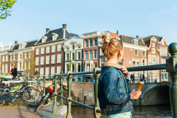 Egy aranyos kislány, egy gyönyörű csatorna Amszterdamban keres kültéri portréja — Stock Fotó