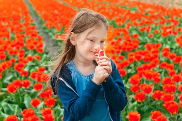 Adorável menina brincando com flores em uma fazenda de tulipas — Fotografia de Stock