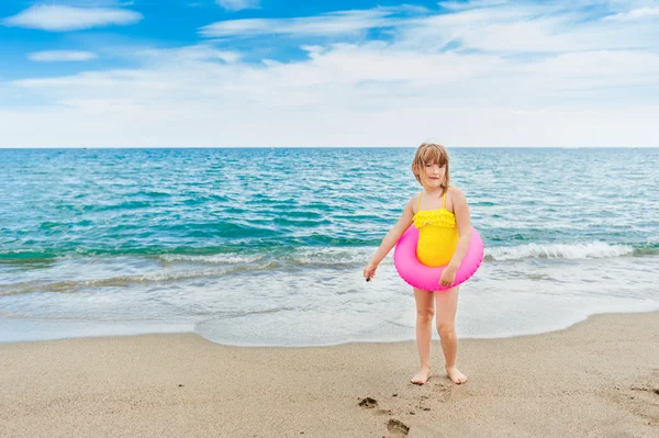 Adorable little girl with pink inflatable ring by the sea on summer vacation — Stock Photo, Image