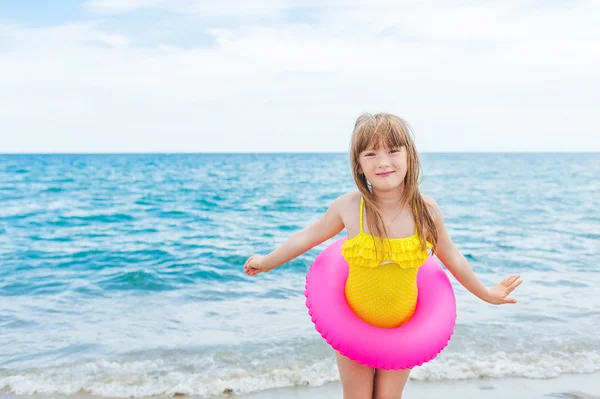 Adorable little girl with pink inflatable ring by the sea on summer vacation — Stock Photo, Image