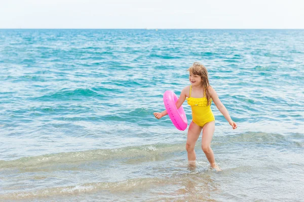 Очаровательная маленькая девочка с розовым надувным кольцом у моря на летних каникулах — стоковое фото