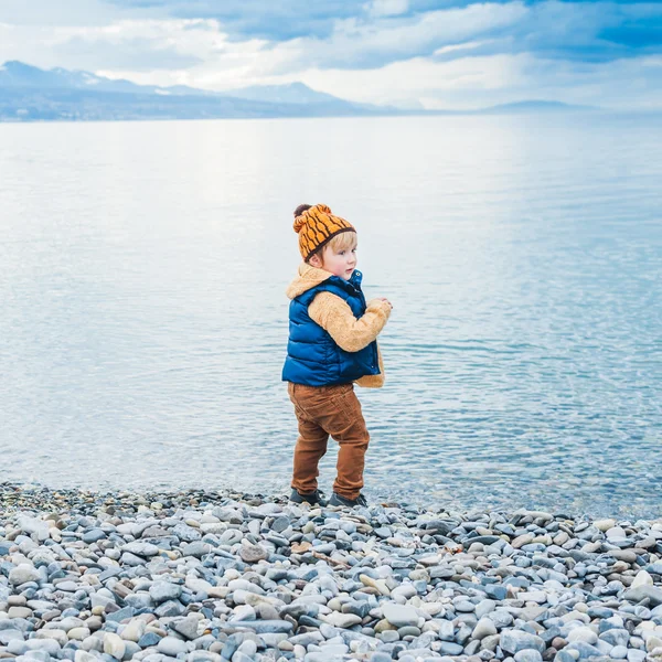 Cute toddler boy playing next to lake on a cold day — Stock Photo, Image