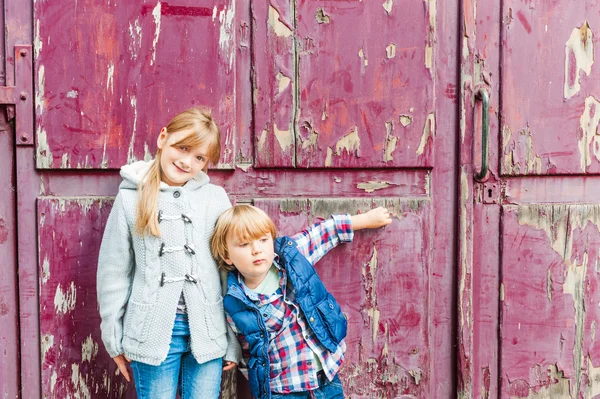 Portrait of two adorable kids outdoors on a street, against old door — Stock Photo, Image