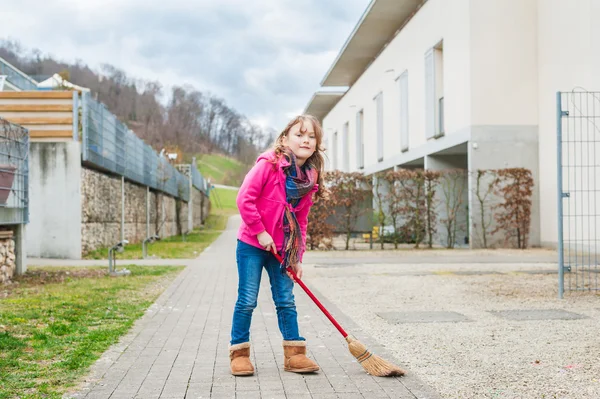 Söt liten flicka svepande bakgården en tidig vårdag — Stockfoto