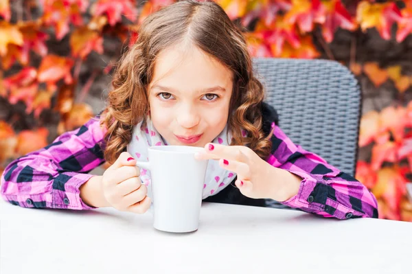 Schattig klein meisje warme chocolademelk drinken op een terras — Stockfoto