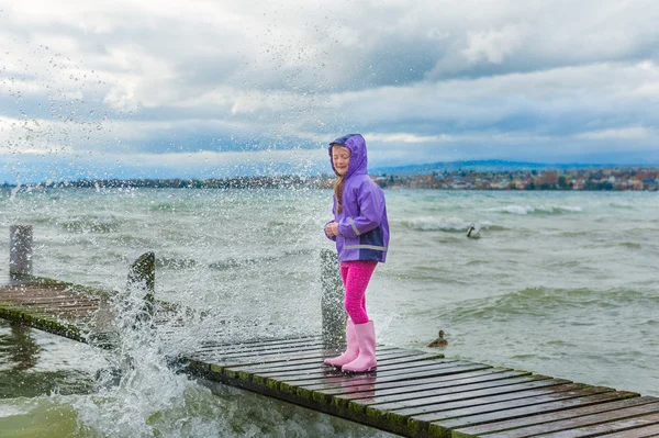 Nettes kleines Mädchen spielt draußen am See bei kaltem Wetter — Stockfoto