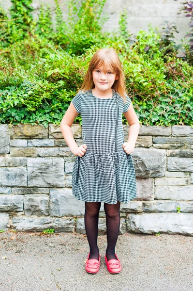 Utomhus porträtt av en söt liten flicka, klädd i klänning och röda skor — Stockfoto