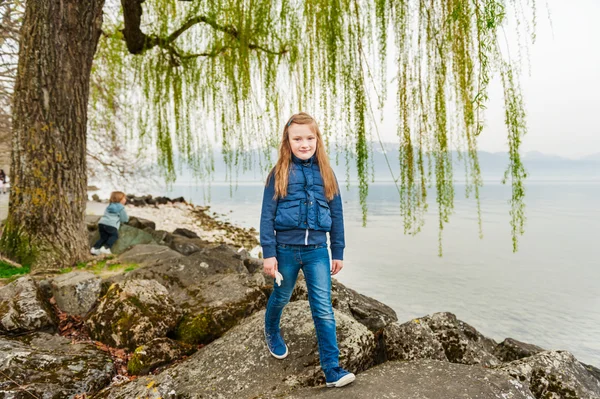 Cute dziewczynka gra obok pięknego jeziora wczesną wiosną — Zdjęcie stockowe