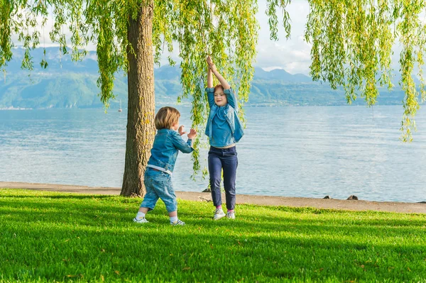 Dvě děti baví venku na pěkný slunečný den, hrál u jezera — Stock fotografie