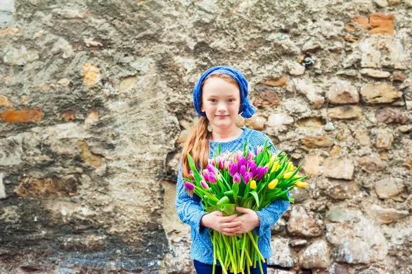 Ritratto all'aperto di una graziosa bambina in una città vecchia con un enorme bouquet di tulipani freschi colorati — Foto Stock