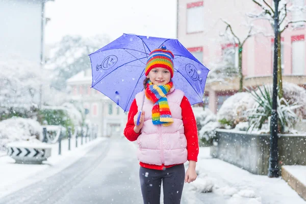 室外肖像的降雪量下的一个城市一个漂亮的小女孩 — 图库照片