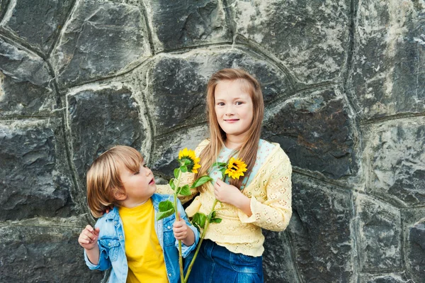 Utomhus porträtt av bedårande barn utomhus, anläggning solrosor — Stockfoto