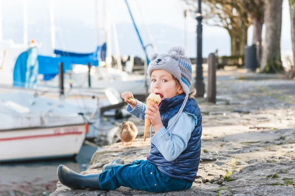 Очаровательный маленький мальчик ест мороженое на улице в холодную погоду — стоковое фото