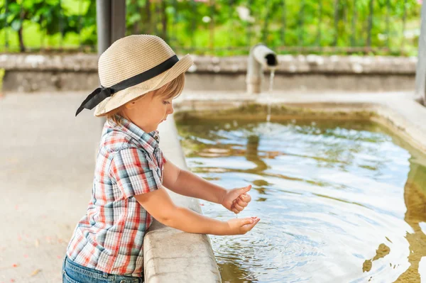 Menino adorável brincando com água em um dia quente de verão — Fotografia de Stock