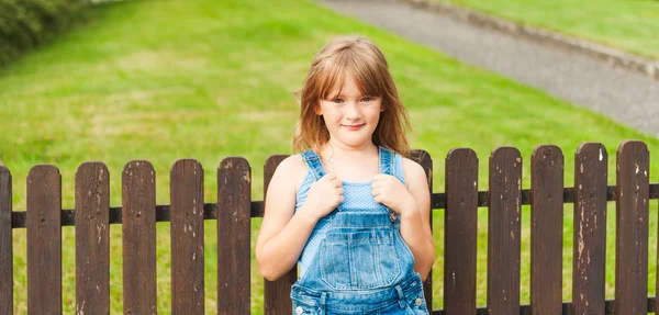 Sommerporträt eines süßen kleinen Mädchens von sieben Jahren am Zaun — Stockfoto