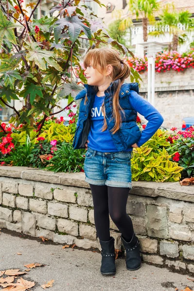 Retrato al aire libre de una linda niña en una ciudad, con chaleco azul y pantalones cortos de mezclilla —  Fotos de Stock