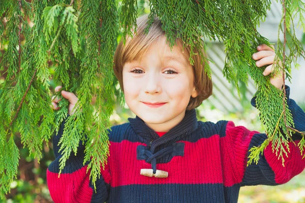 Carino bambino nascosto dietro i rami degli alberi, divertirsi all'aperto — Foto Stock