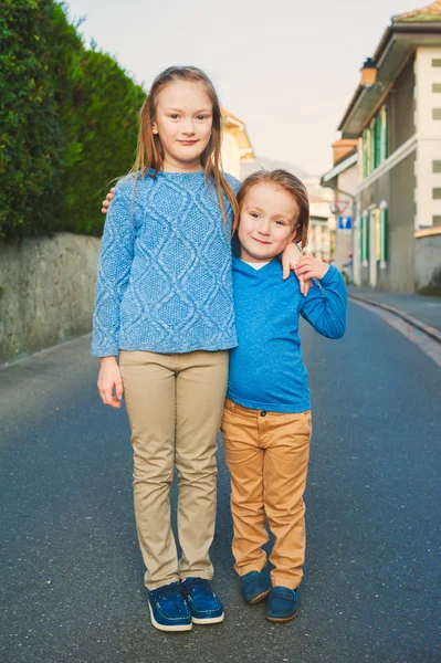 Två bedårande barn i en stad, flicka och hennes lillebror, klädd i blå och beige kläder och mockasiner — Stockfoto