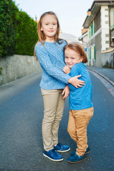 Dvě roztomilé děti v městě, dívka a její mladší bratr, nosí modré a béžové šaty a mokasíny — Stock fotografie