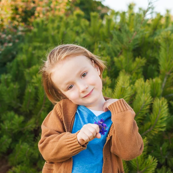 Retrato ao ar livre de um menino bonito de 4 anos de idade, segurando primeira primavera flores violetas — Fotografia de Stock