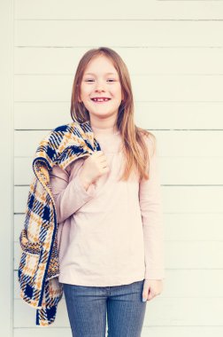 Moda portre sevimli küçük bir kızın 7 yaşında, sarı ve mavi ekose hırka, holding pembe gömlek giymiş görüntü tonda