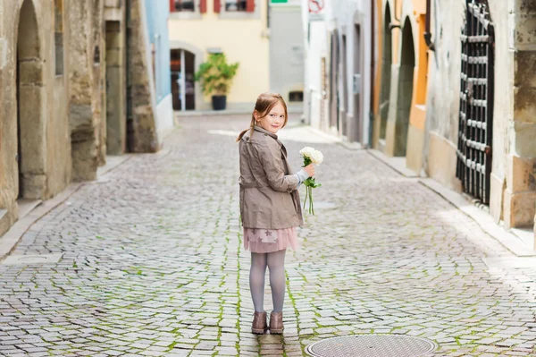 Ritratto all'aperto di una graziosa bambina con mazzo di rose bianche, guardando indietro sopra la spalla — Foto Stock