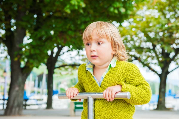 Adorável criança menino se divertindo no playground, vestindo pulôver verde brilhante — Fotografia de Stock