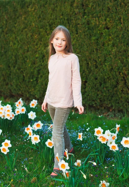 Menina bonito de 7 anos de idade brincando no parque da primavera entre flores narcisos — Fotografia de Stock