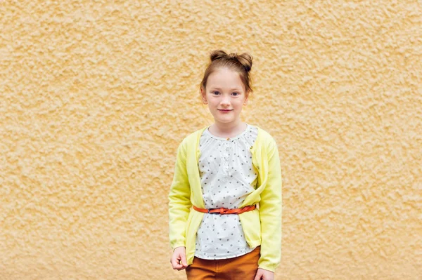 Retrato de moda de una linda niña de 7 años, con blusa, chaqueta amarilla, cinturón naranja — Foto de Stock