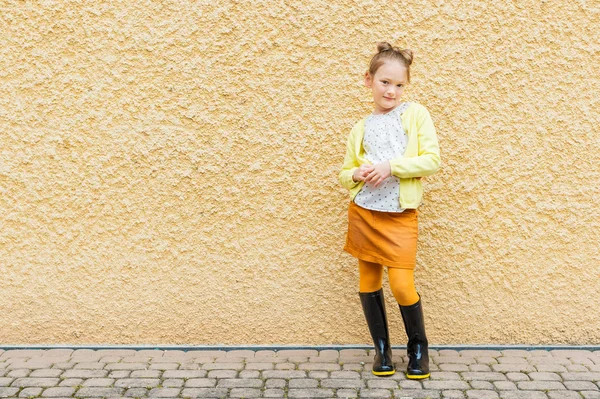 Portret moda słodkie dziewczynki 7 lat, noszenie bluzka, kurtka żółty, pomarańczowy spódnica i buty czarny deszcz — Zdjęcie stockowe