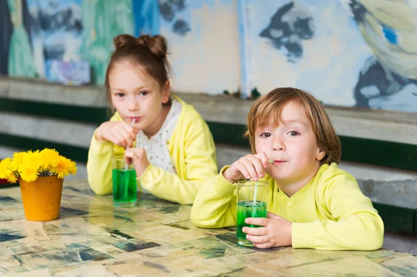 Dos lindos niños bebiendo jarabe de menta verde en un café — Foto de Stock