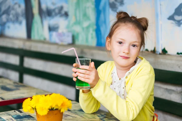 Adorável menina bebendo xarope de hortelã em um café, vestindo casaco amarelo — Fotografia de Stock