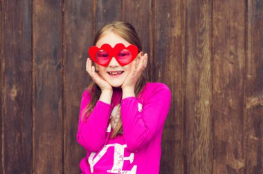 Komik büyük kalp giyen küçük şirin bir kız portresi güneş gözlüğü şeklinde