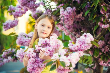 Günbatımı Japon kiraz çiçeği çiçek ile oynayan sevimli küçük kız portresi bahar