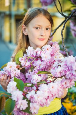 Günbatımı Japon kiraz çiçeği çiçek ile oynayan sevimli küçük kız portresi bahar