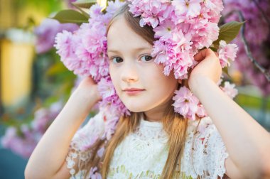 Günbatımı Japon kiraz çiçeği çiçek ile oynayan sevimli küçük kız portresi bahar