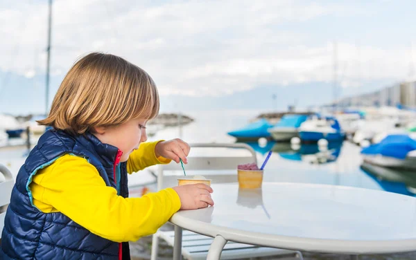 Mooie blonde jongen eten een ijsje met een meer-poort op de achtergrond — Stockfoto