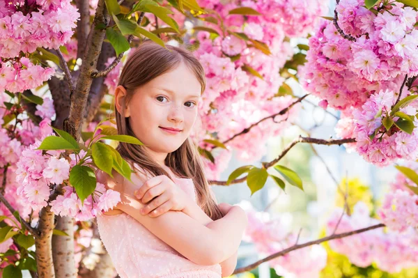 Utomhus våren porträtt av en söt liten tjej, mellan blommor av ett japanskt körsbär i blossom — Stockfoto