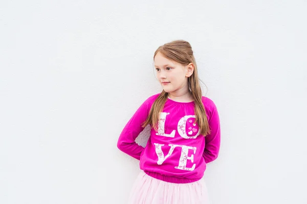 Egy szép kislány, világos rózsaszín pólót viselő portréja — Stock Fotó