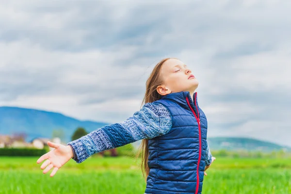 風のフィールドで遊ぶ愛らしい少女腕大きく開いて — ストック写真