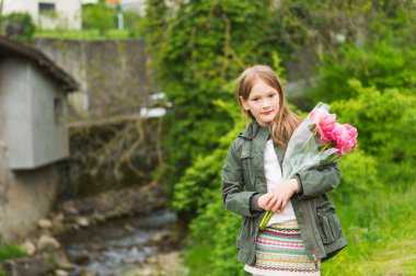 Açık pembe peonies buket tutan haki parka, giyen sevimli küçük bir kız, portresi