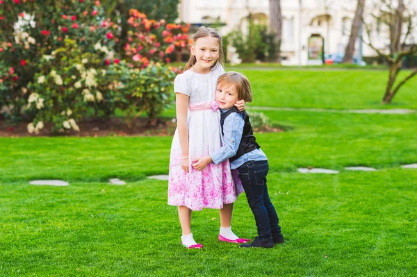 Ritratto all'aperto di due simpatici bambini che giocano nel parco, indossando abiti da festa — Foto Stock