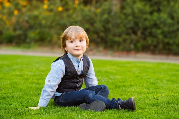 4 歳、夕暮れ、公園の芝生の上に座っての愛らしい男の子の屋外のポートレート — ストック写真