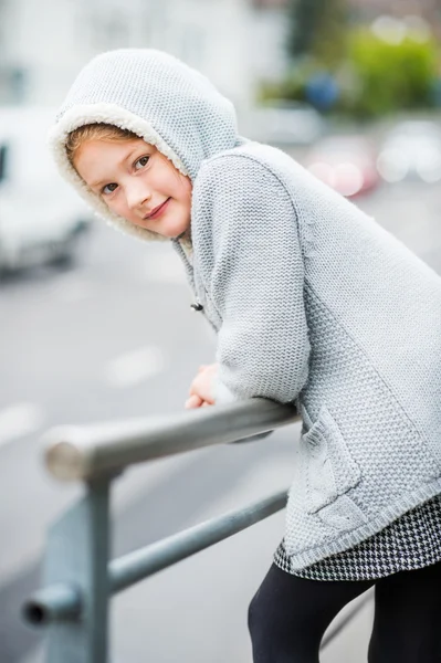 Außenporträt eines niedlichen kleinen Mädchens in einer Stadt, das eine graue Strickjacke trägt — Stockfoto