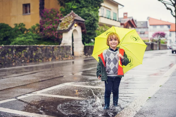 Cute little boy with umbrella playing in the puddle — Stock Photo, Image