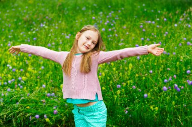 Pembe kazak giyen bir parkta oynayan sevimli küçük kız