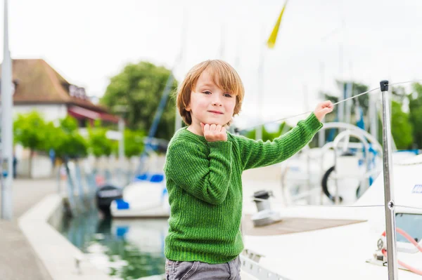 Retrato ao ar livre de um menino bonito brincando junto ao lago, vestindo pulôver verde — Fotografia de Stock
