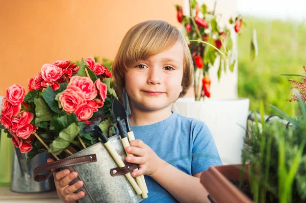 Ragazzino carino che gioca con gli attrezzi da giardino sul balcone — Foto Stock